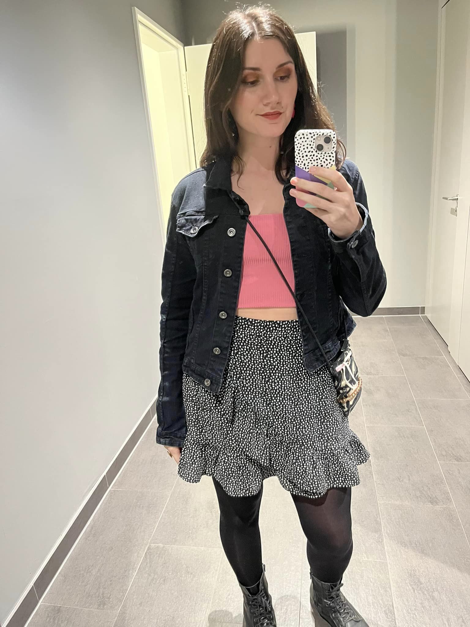 A mirror selfie of Jillian in a pink top and black skirt